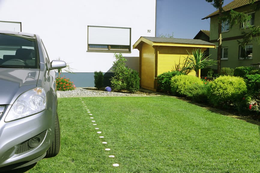 Osobni automobil parkiran na Guttagarden travnoj rešetki s potpuno izraslom travom ispred privatne kuće