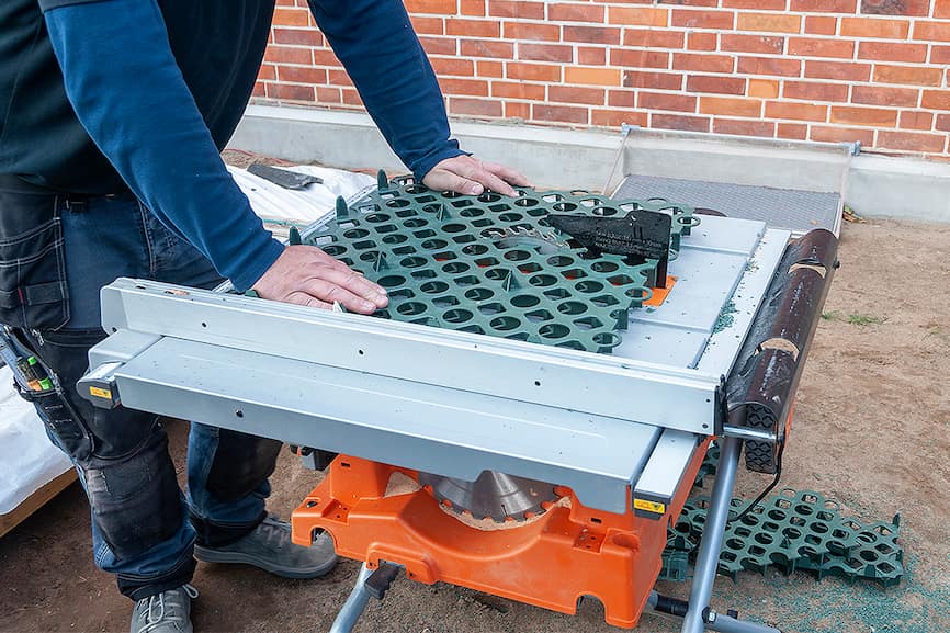 Rezanje Guttagarden travne rešetke cirkularnom pilom s postoljem uz vidljive odrezane komade i plastične strugotine