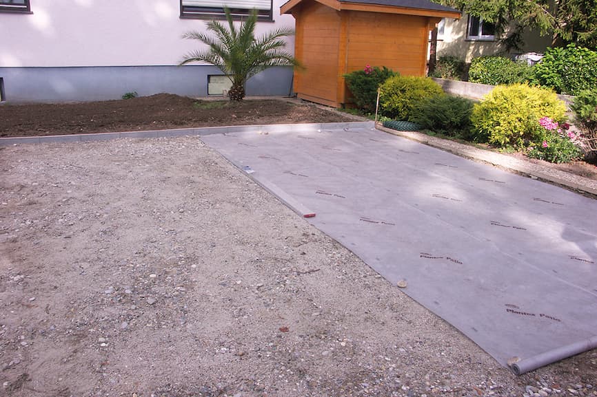 Postavljanje geotekstila preko zbijenog nosivog sloja tijekom pripreme parkirališta za travnu rešetku