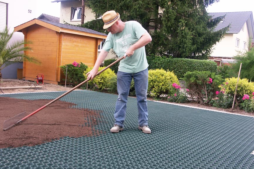 Punjenje saća travne rešetke zemljom pomoću grablji nakon postavljanja rešetki