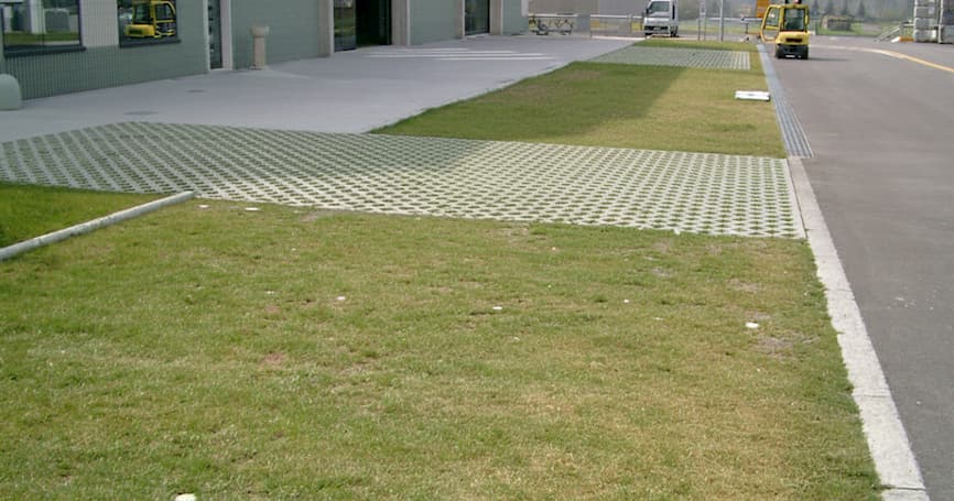 Betonska travna rešetka s posađenom travom uz industrijski objekt i prometnicu