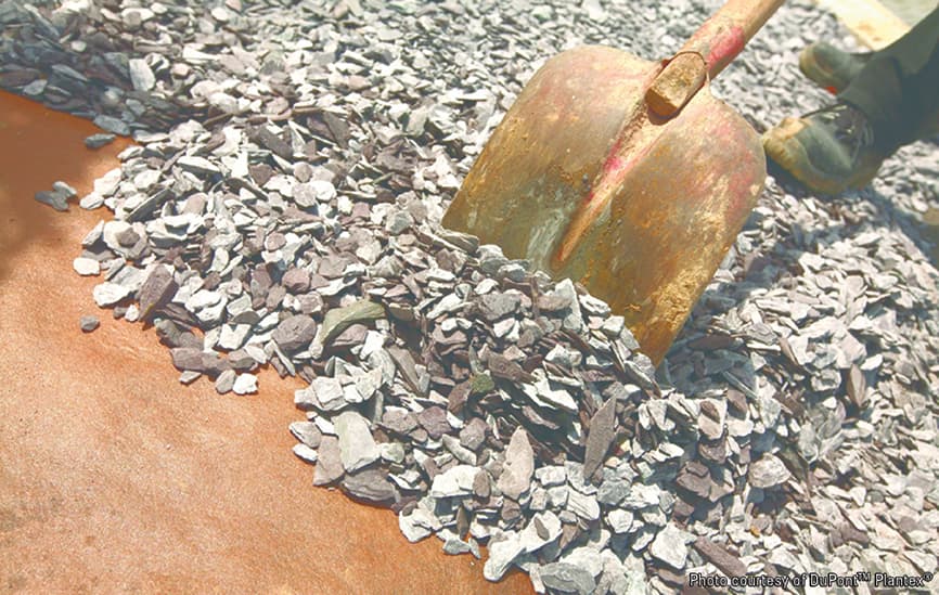 Postavljanje kamenog sloja preko DuPont Plantex Gold folije protiv korova uz pomoć lopate